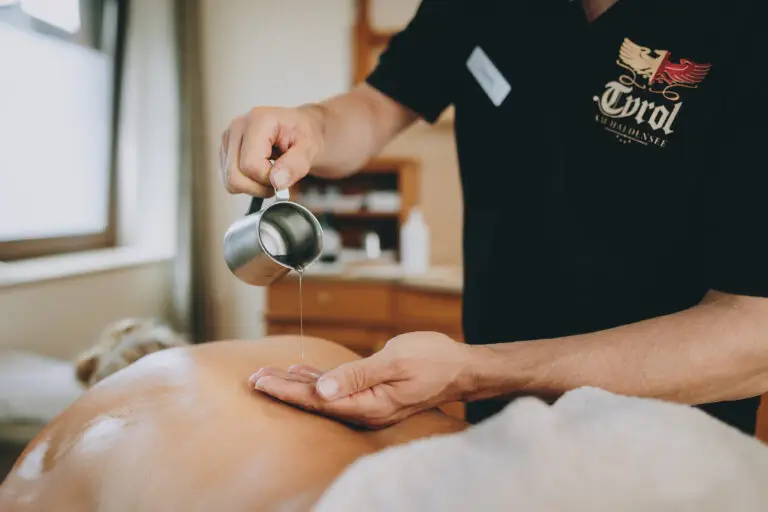 Masseur der Öl aus einer Kanne in seine Hand schüttet.