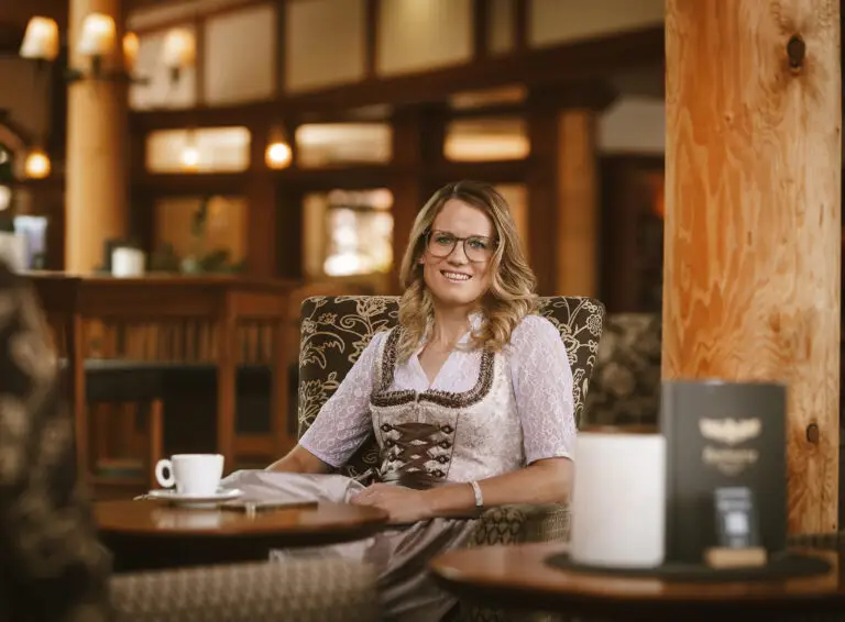 Portrait von Martina Barbist lächelnd mit einem Kaffee in einem Sessel sitzend.