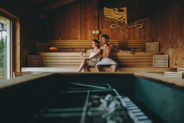 Pärchen sitzt in der Sauna und blickt glücklich nach draußen.